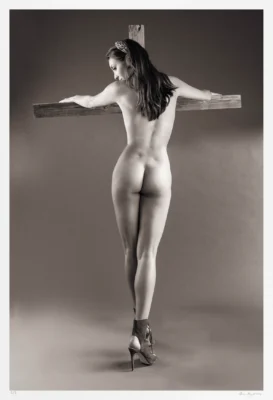 In this black and white nude, symbolism plays a principal role. Wooden planks are visible, the unmistakable shape of a robust cross is discernible.