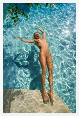 In this art photograph a nude woman drifts on her back in a gleaming blue swimming pool. Her only interest seemingly is this joyful moment of sun and water